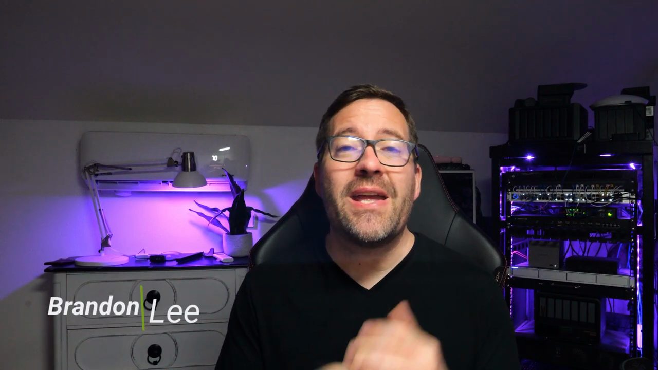 Brandon Lee nói trước camera, phía sau là tủ rack home lab có đèn tím