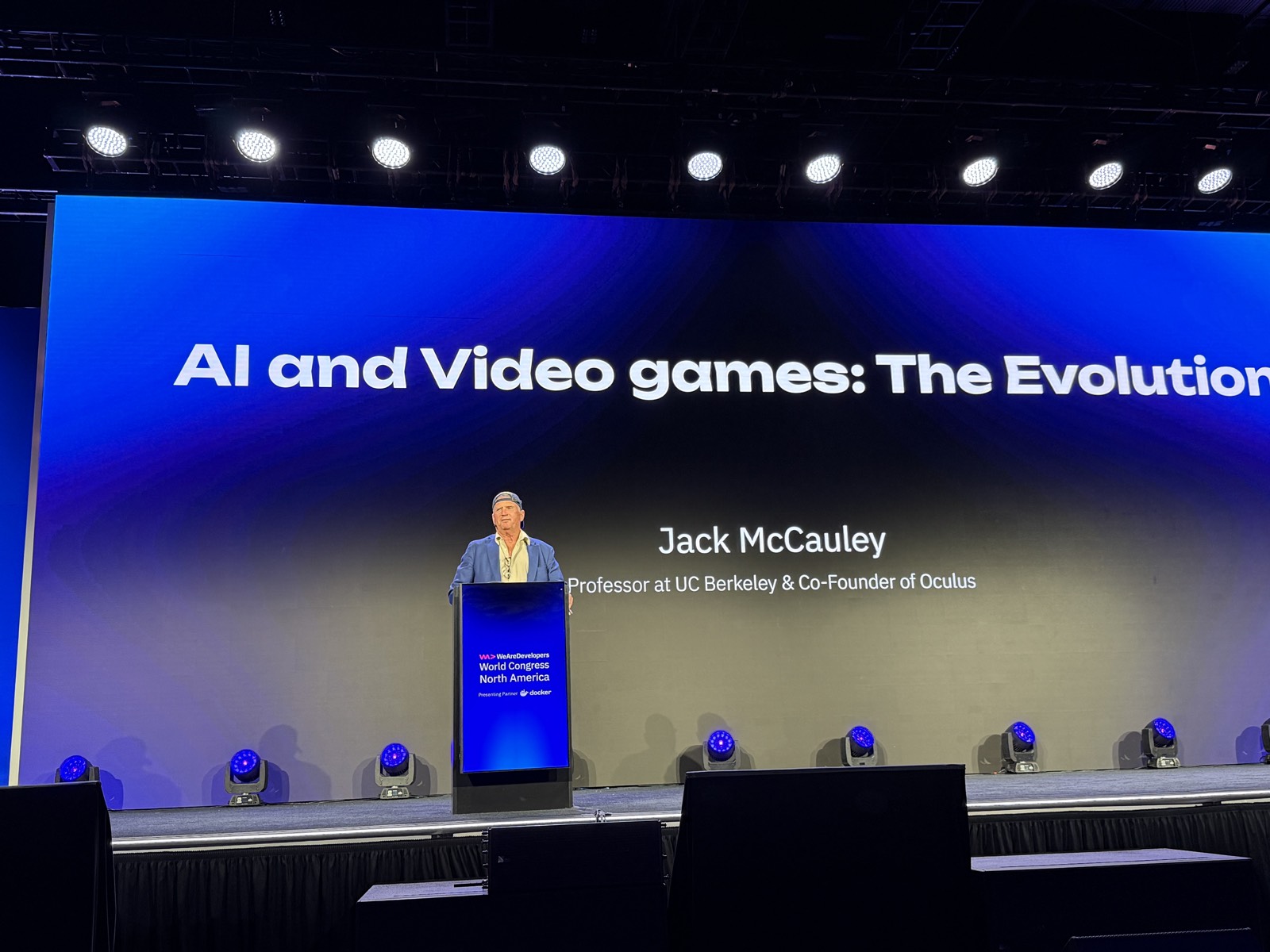 Jack McCauley đứng sau bục, màn hình ghi AI and Video games: The Evolution