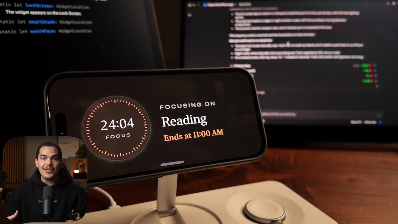 iPhone nằm ngang trên đế sạc ở chế độ StandBy: mặt đồng hồ 24:04 FOCUS, chữ FOCUSING ON Reading, Ends at 11:00 AM