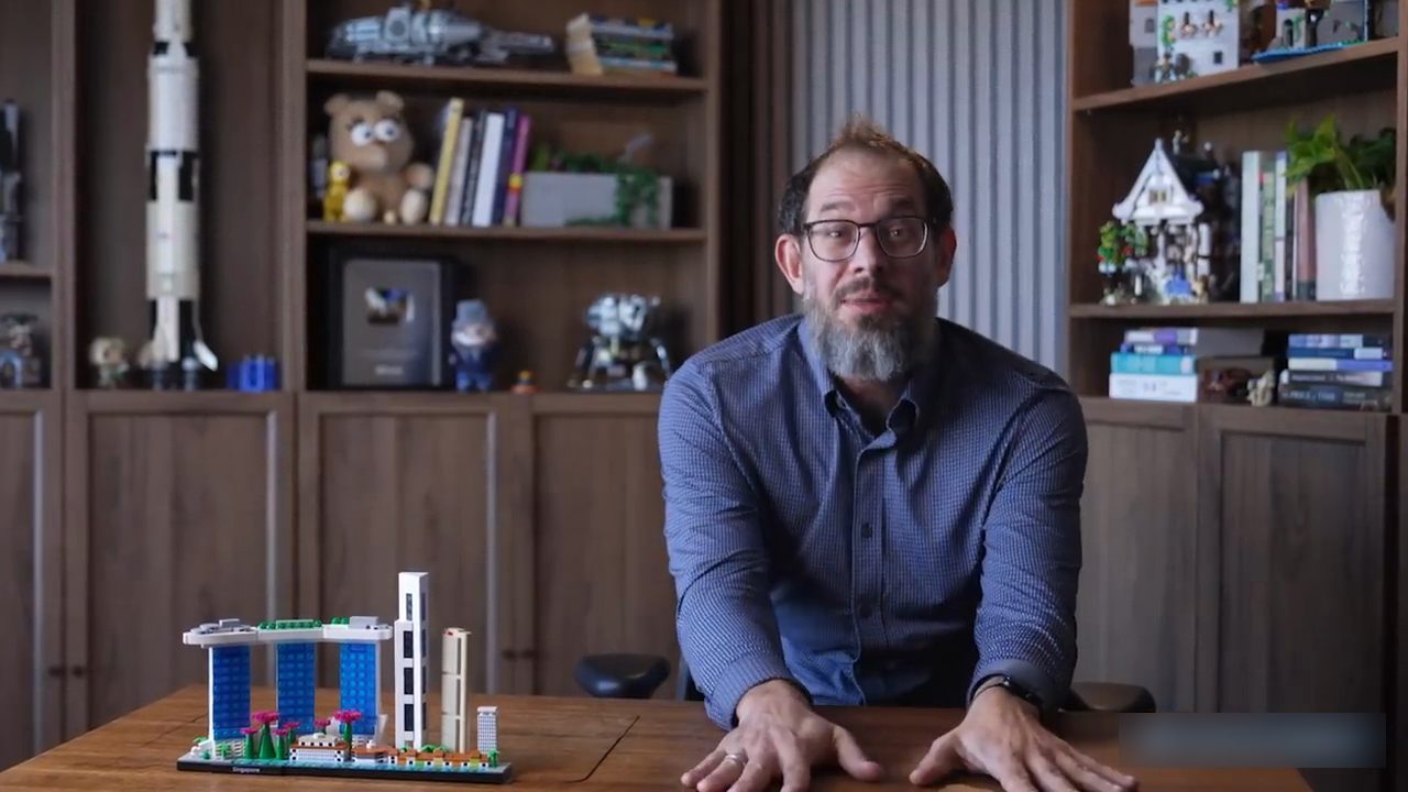 Nate B Jones ngồi sau bàn gỗ, phía sau là kệ sách và các mô hình lắp ghép